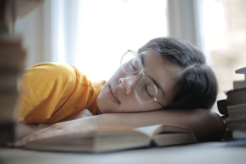 精疲力竭的女学生在图书馆的桌上睡觉 · 免费素材图片