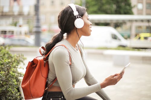 女人在听音乐时拿着智能手机的浅焦点照片 · 免费素材图片
