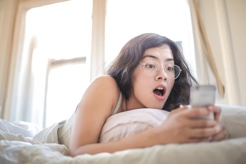 躺在床上拿着智能手机的女人 · 免费素材图片