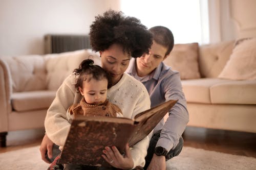 女人抱着她的孩子的棕色书的照片 · 免费素材图片