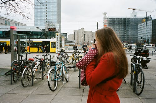 不可识别的女人谈到城市街道的人行道上的智能手机 · 免费素材图片