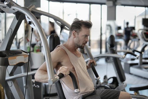 强大的运动员与肩部推举机在健身房锻炼 · 免费素材图片
