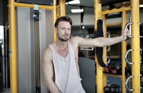 休息在现代健身房运动机附近的严重肌肉男运动员 · 免费素材图片