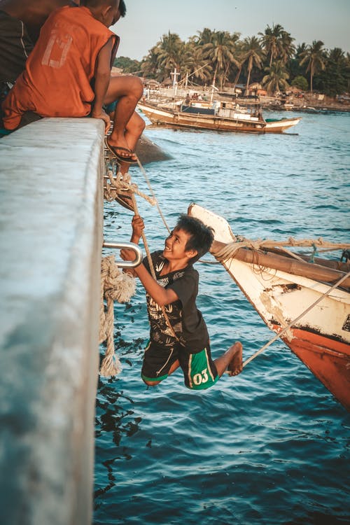 在热带海中岁的船上玩的男孩 · 免费素材图片