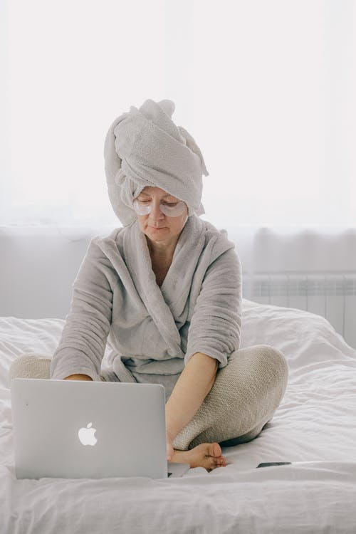 老年的女人在床上使用笔记本电脑 · 免费素材图片