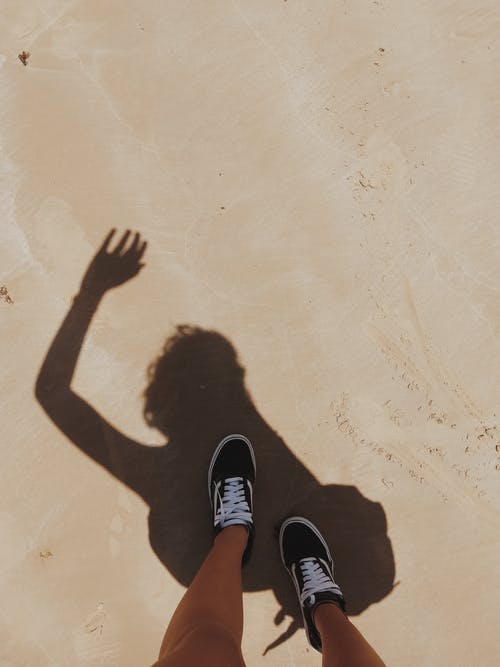 黑色背心和黑色短裤站在棕色沙滩上的女人 · 免费素材图片