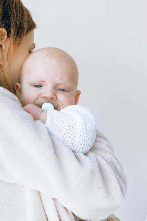 在轻的演播室播种镇定用安慰者的妈妈困的婴儿用在嘴的安慰者 · 免费素材图片