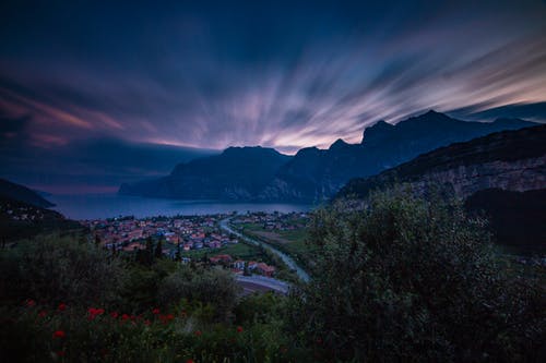 城市景观附近的山脉和大海在日落时色彩斑colorful的天空下 · 免费素材图片