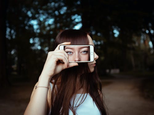 女人拿着智能手机与女人的脸背景 · 免费素材图片