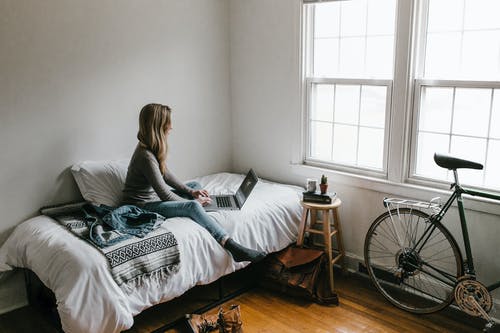 坐在床上的灰色衬衫的女人 · 免费素材图片