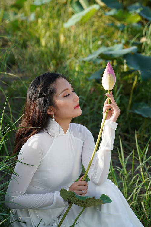 拿着花的白色长袖礼服的妇女 · 免费素材图片