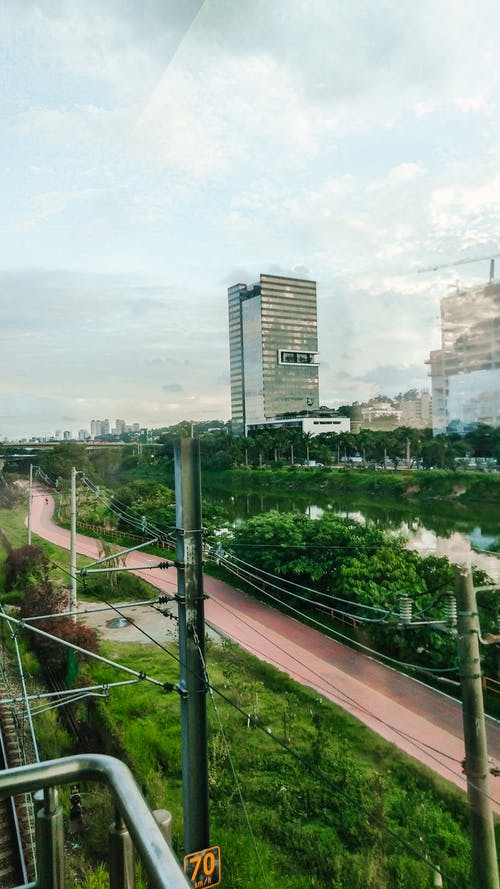 绿树和城市道路附近的多层建筑立面 · 免费素材图片