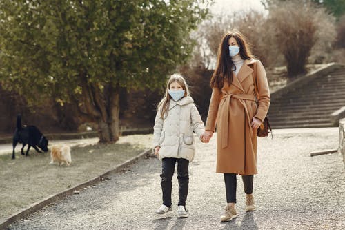 母亲带着女儿在口罩在公园散步 · 免费素材图片