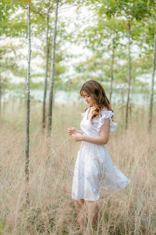 站在棕色的草地上的白色连衣裙的女人 · 免费素材图片