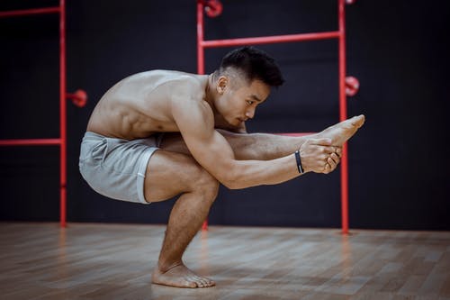 灵活的亚洲年轻男子，在哈达瑜伽训练期间做平衡体式 · 免费素材图片
