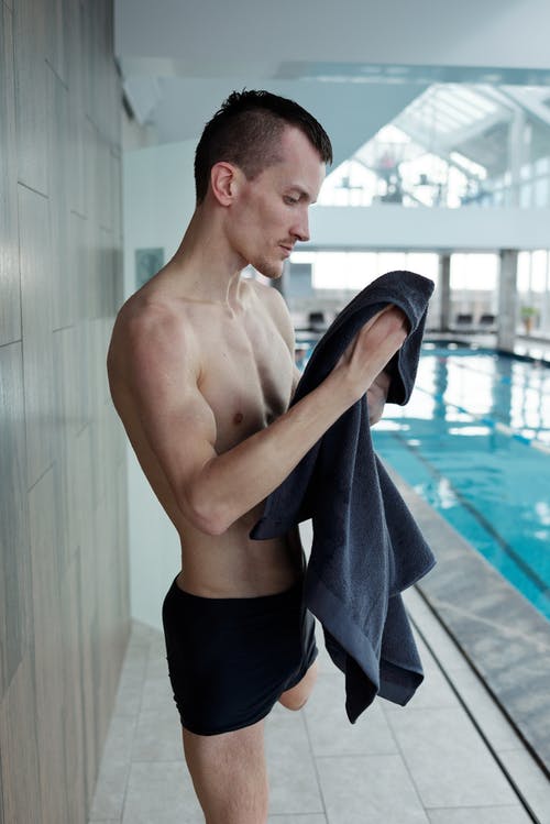 男子手持毛巾在游泳池旁 · 免费素材图片