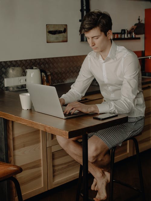 坐在椅子上使用macbook的白色礼服衬衫的女人 · 免费素材图片