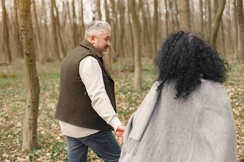 男人和女人在森林散步时手牵着手的照片 · 免费素材图片