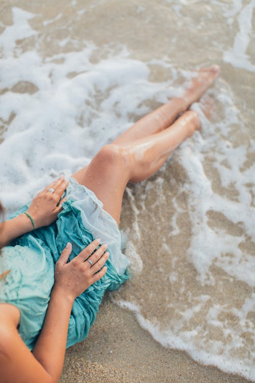 庄稼女士坐在挥舞着大海的沙滩上 · 免费素材图片