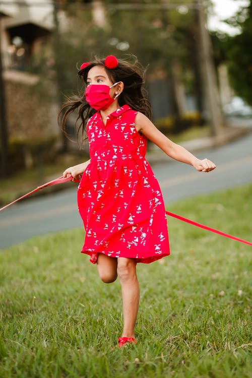 顽皮的女孩，在面具沿着草坪跑 · 免费素材图片