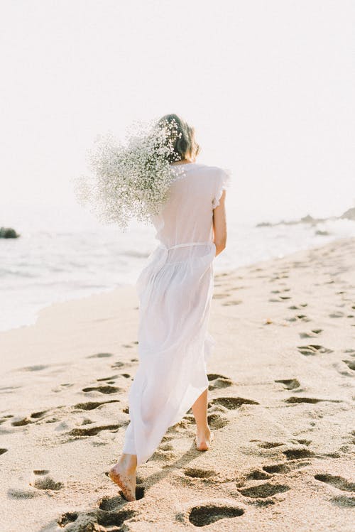 在沙滩上散步的白裙子的女人 · 免费素材图片