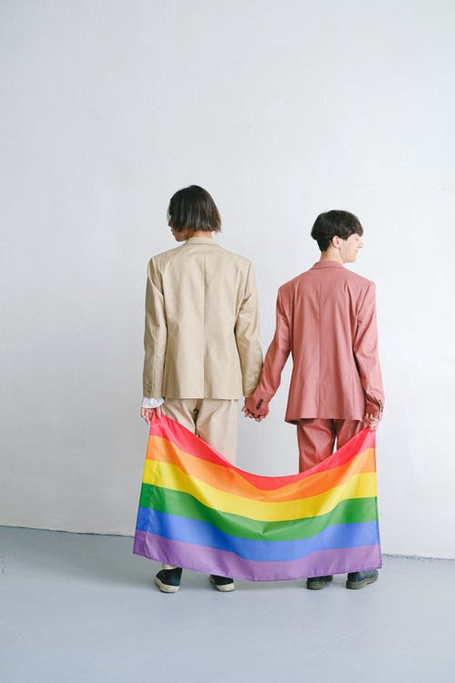 穿着西装拿着同性恋骄傲旗帜的男人 · 免费素材图片