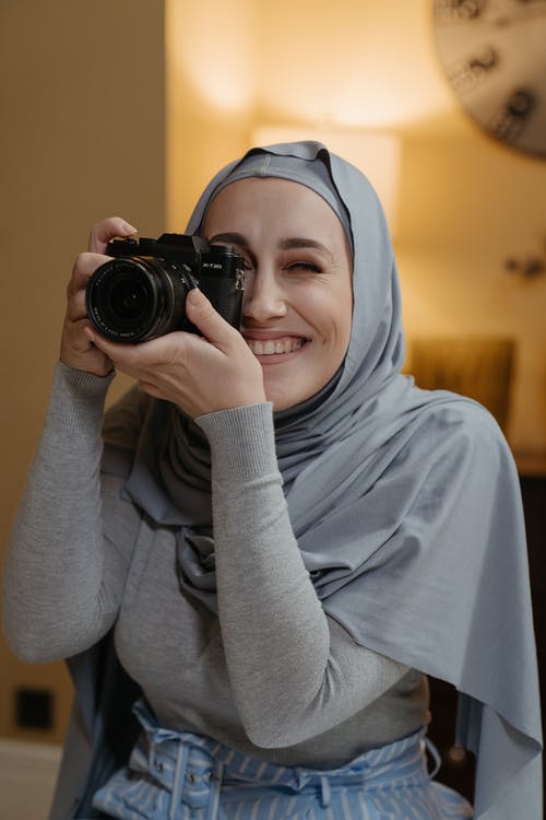 拿着黑色相机的灰色头巾的女人 · 免费素材图片