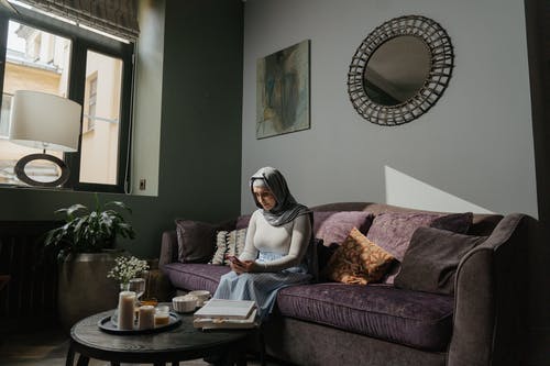 白色头巾的女人坐在棕色沙发上 · 免费素材图片