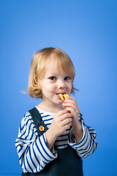 黑色和白色条纹长袖衬衫吃黄色食物的女孩 · 免费素材图片