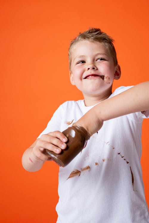 拿着巧克力罐的白色船员脖子t恤杉的男孩 · 免费素材图片