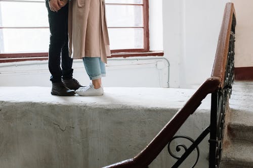 棕色外套和蓝色牛仔牛仔裤，站在灰色的混凝土楼梯上的女人 · 免费素材图片