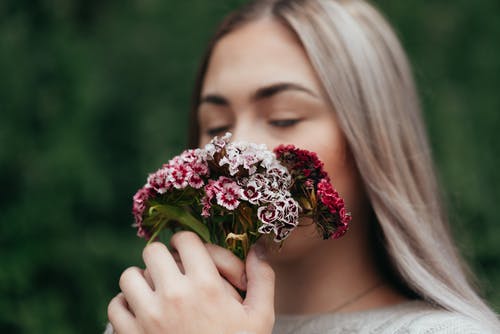 温柔的女人，享受着盛开的鲜花的味道 · 免费素材图片