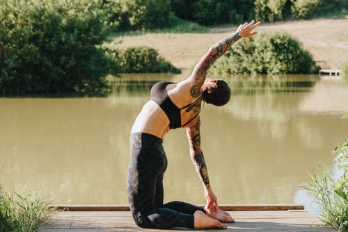 匿名在码头的妇女实践的瑜伽反对湖 · 免费素材图片