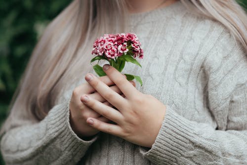 和平女性站与手中的粉红色花朵 · 免费素材图片
