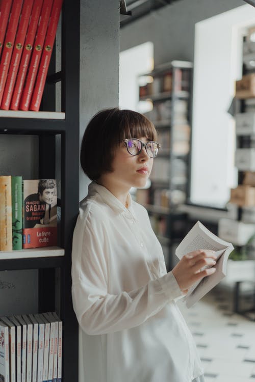 拿着白皮书的白色礼服衬衣的妇女 · 免费素材图片