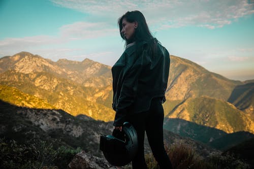 绿色连帽衫和黑色的裤子，坐在岩石上的女人 · 免费素材图片