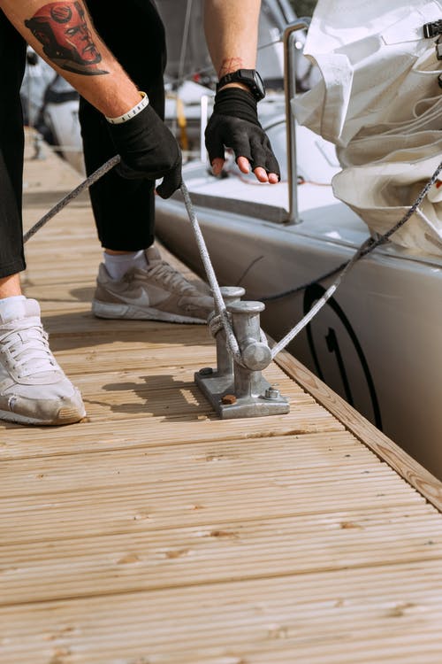 黑裤子和白色耐克运动鞋站在棕色木制码头上的人 · 免费素材图片