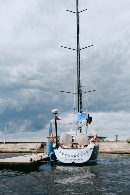 多云的天空下的码头上的白色和蓝色船 · 免费素材图片