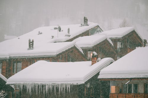 人们站在积雪覆盖的屋顶上 · 免费素材图片
