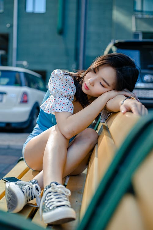 梦幻般的亚裔女子，在城市的长凳上休息 · 免费素材图片