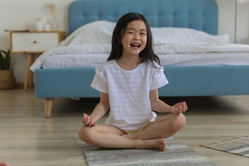 快乐的亚洲女孩笑着，休息在房间里，双腿交叉 · 免费素材图片