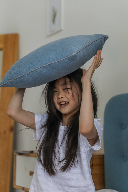 有枕头顶上的愉快的亚裔女孩 · 免费素材图片