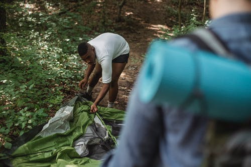 男性的非洲裔美国背包客在森林里搭帐篷 · 免费素材图片
