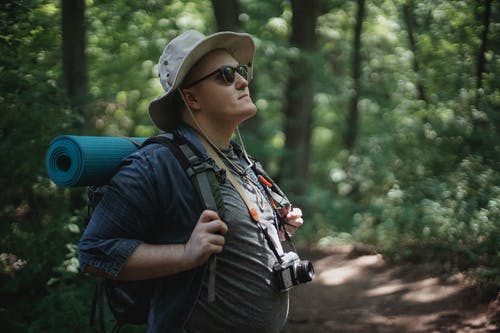 太阳镜探索夏季树林的男性背包客 · 免费素材图片