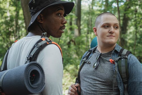 年轻的多种族男性旅客在徒步旅行期间站在树林里 · 免费素材图片