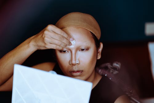 亚洲女人化妆，看着镜子 · 免费素材图片