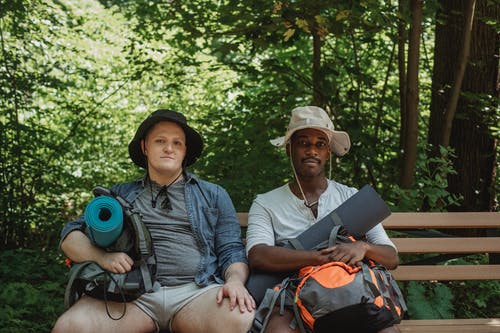 多族裔朋友在森林里的长椅上休息的背囊 · 免费素材图片