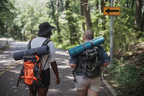 无法识别多样男性徒步旅行者背着背包走在路上 · 免费素材图片