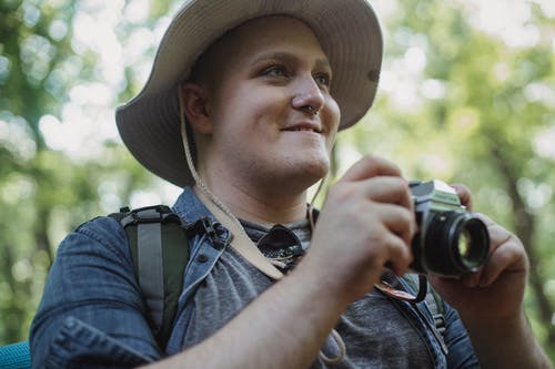 在树林里种有相机拍照的微笑旅游 · 免费素材图片