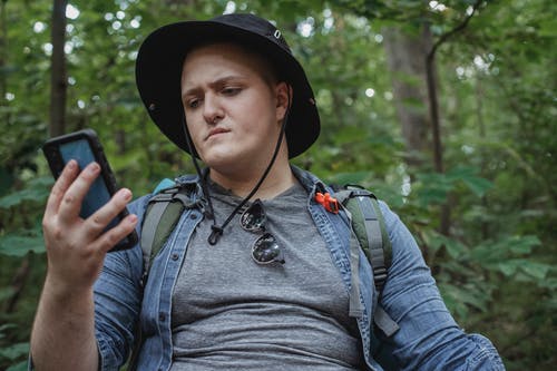 细心的游客在夏季森林看智能手机 · 免费素材图片